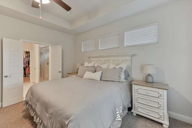 bedroom featuring light carpet, a walk in closet, a closet, and ceiling fan