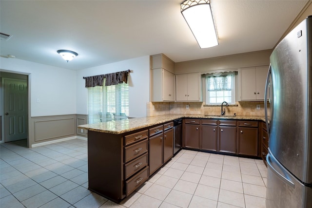 508 Squires Ln, Krugerville, TX 76227 - kitchen with wainscoting, dishwasher, light tile patterned floors, freestanding refrigerator, and a peninsula