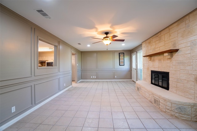 508 Squires Ln, Krugerville, TX 76227 - unfurnished living room featuring a stone fireplace, ceiling fan, a decorative wall, and visible vents