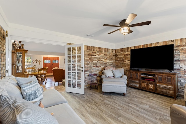 living room with wood-type flooring, ceiling fan, and brick wall