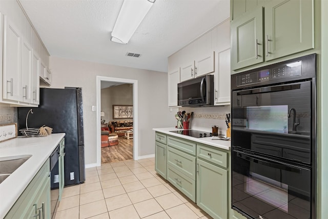 kitchen with a textured ceiling, white cabinets, black appliances, and light tile patterned floors