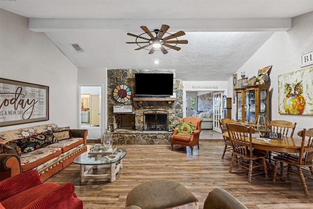 living room with vaulted ceiling with beams, ceiling fan, a fireplace, and hardwood / wood-style flooring