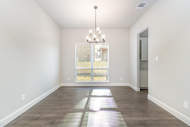 unfurnished dining area featuring dark wood-type flooring and a chandelier