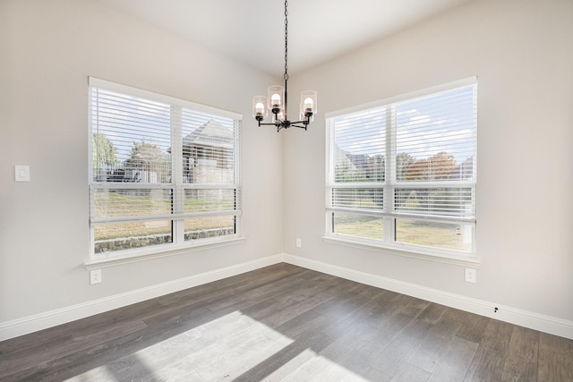 unfurnished dining area with dark hardwood / wood-style flooring, a wealth of natural light, and a notable chandelier