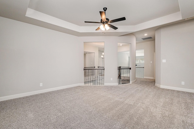 spare room with carpet flooring, ceiling fan, and a tray ceiling