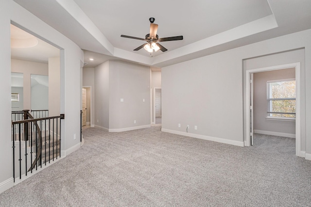 carpeted spare room featuring ceiling fan and a tray ceiling