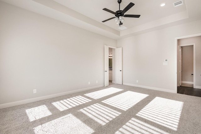 unfurnished room with carpet flooring, a tray ceiling, and ceiling fan