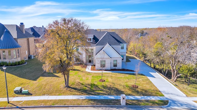 view of front of property with driveway, stone siding, a standing seam roof, and a front yard