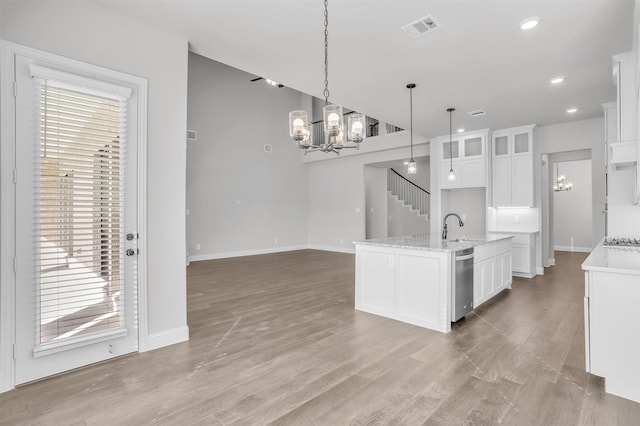 kitchen featuring appliances with stainless steel finishes, tasteful backsplash, a kitchen island with sink, decorative light fixtures, and white cabinetry