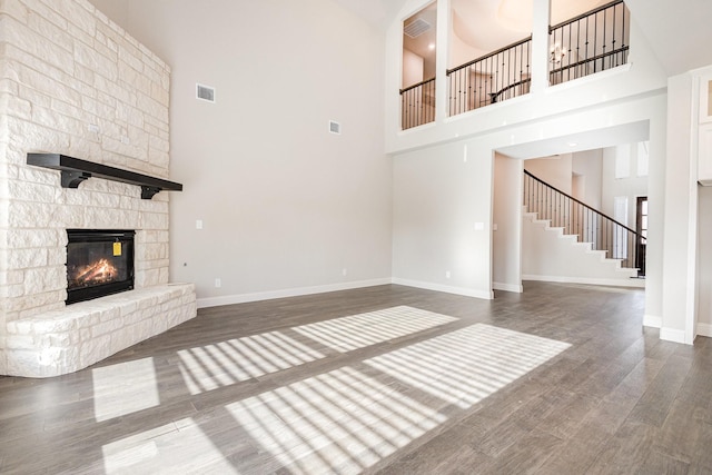 unfurnished living room featuring dark hardwood / wood-style floors, a towering ceiling, and a fireplace