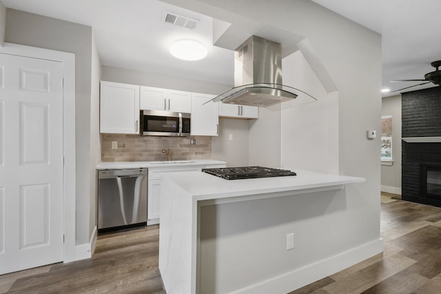 kitchen featuring island exhaust hood, appliances with stainless steel finishes, white cabinets, and hardwood / wood-style floors