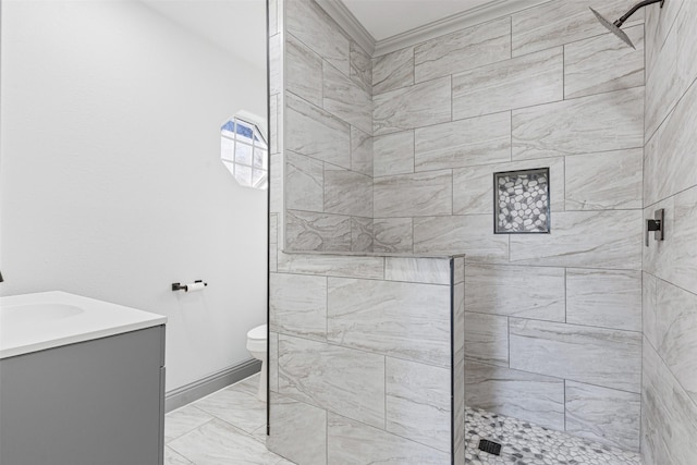 bathroom featuring a tile shower, vanity, and toilet