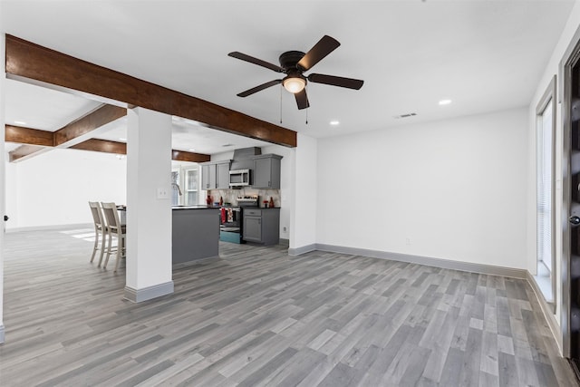 unfurnished living room with beam ceiling, light hardwood / wood-style floors, and ceiling fan