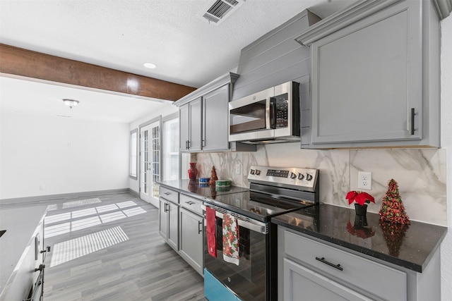 kitchen with gray cabinetry, backsplash, light wood-type flooring, and stainless steel appliances