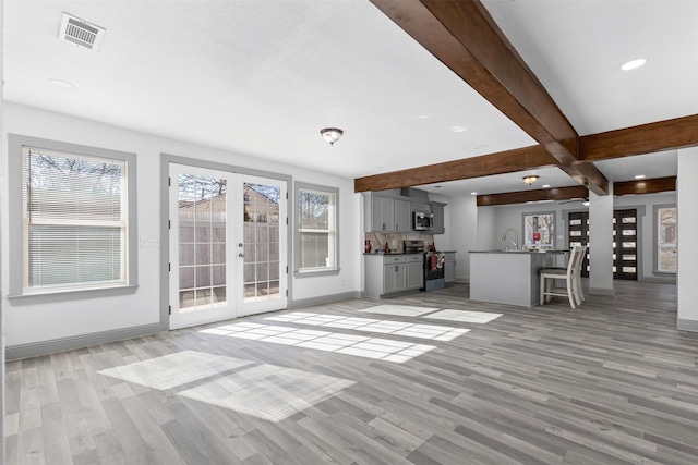 unfurnished living room featuring plenty of natural light, sink, and light hardwood / wood-style flooring