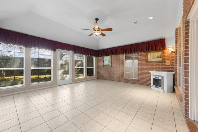 unfurnished living room featuring light tile patterned floors, ceiling fan, and brick wall