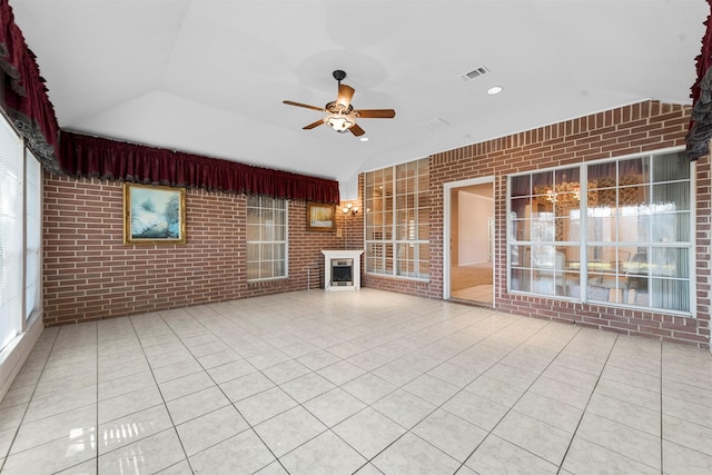 unfurnished living room with tile patterned floors, ceiling fan, brick wall, and vaulted ceiling