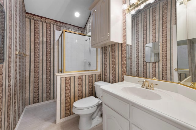 bathroom with tiled shower, hardwood / wood-style floors, vanity, and toilet