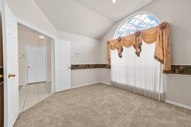 unfurnished room featuring light carpet and vaulted ceiling