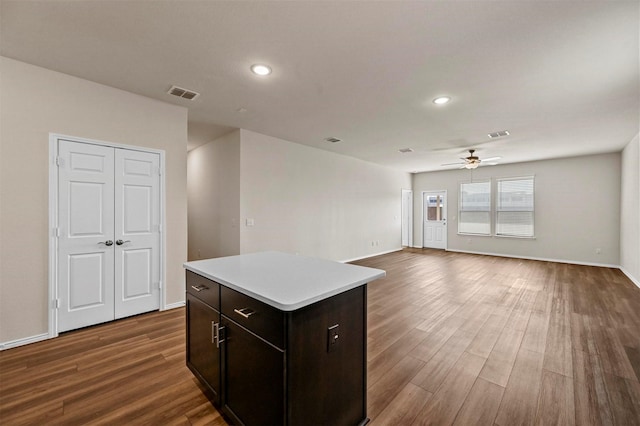 kitchen with dark brown cabinets, a kitchen island, ceiling fan, and dark wood-type flooring