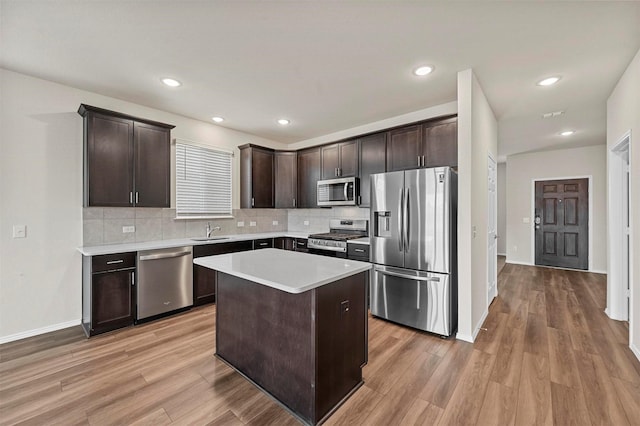 kitchen with appliances with stainless steel finishes, a kitchen island, dark brown cabinets, and sink