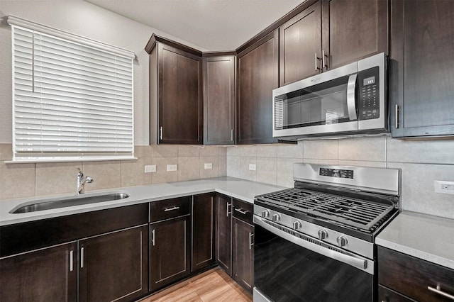 kitchen featuring sink, decorative backsplash, light hardwood / wood-style floors, dark brown cabinetry, and stainless steel appliances