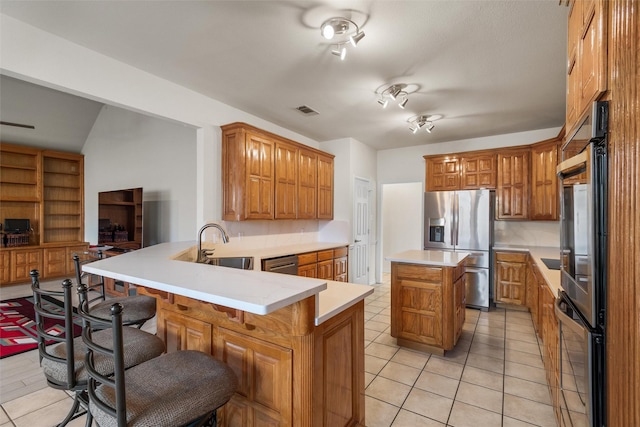 kitchen featuring a kitchen breakfast bar, sink, a kitchen island, kitchen peninsula, and stainless steel appliances