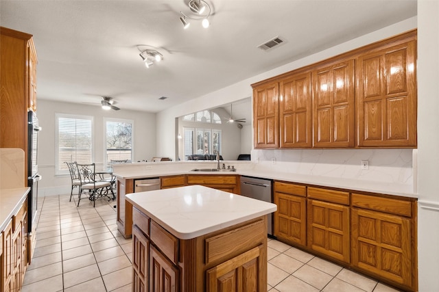 kitchen with kitchen peninsula, stainless steel dishwasher, ceiling fan, sink, and a center island