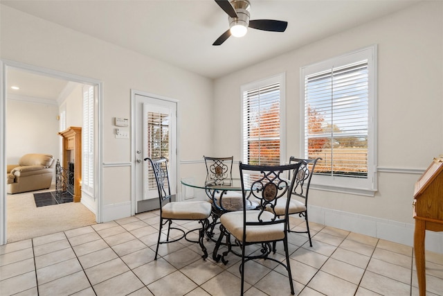 dining space featuring ceiling fan, light tile patterned flooring, a fireplace with flush hearth, and baseboards