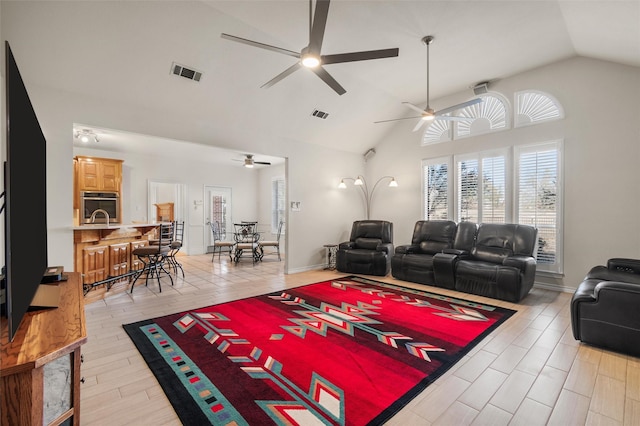 living room featuring ceiling fan, high vaulted ceiling, and light hardwood / wood-style flooring