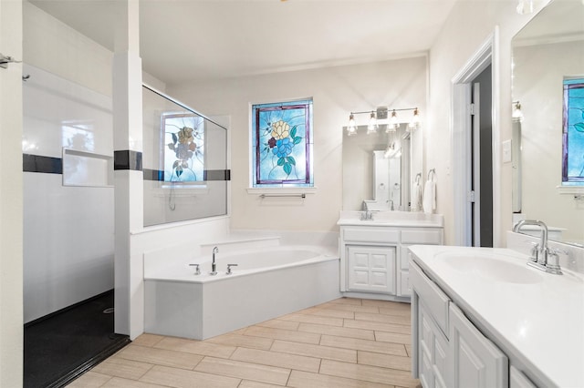 bathroom featuring a garden tub, wood tiled floor, two vanities, and a sink