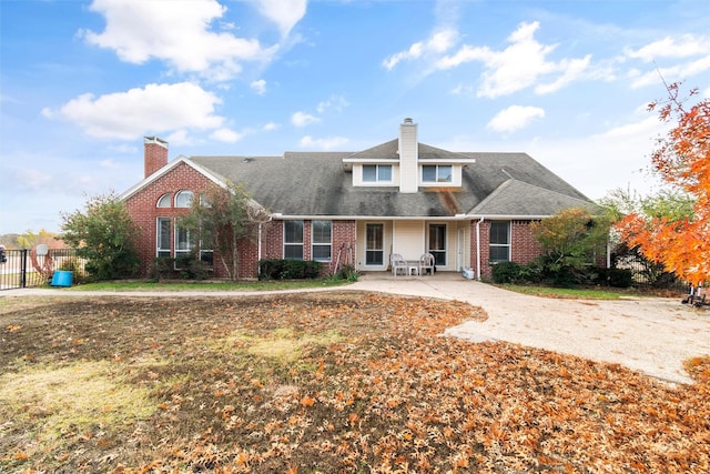 view of front of house featuring brick siding, fence, and a chimney