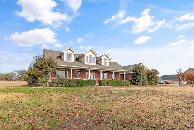 new england style home featuring brick siding and a front lawn