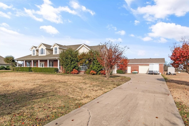 view of front facade featuring brick siding, covered porch, a front yard, a garage, and driveway