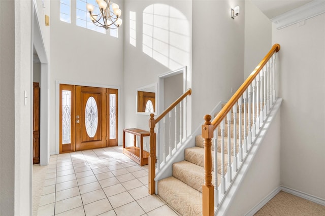 tiled entryway with a notable chandelier, a towering ceiling, and ornamental molding