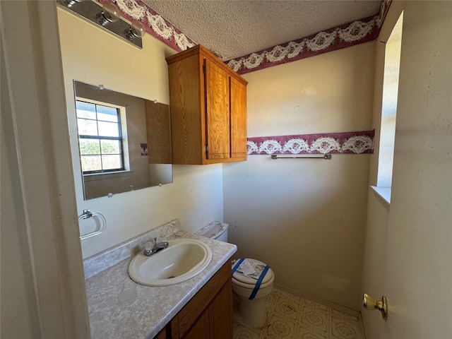 bathroom featuring vanity, toilet, and a textured ceiling