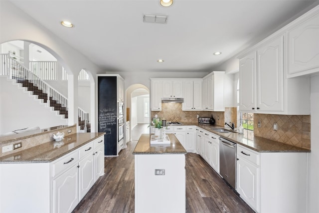 kitchen featuring white cabinets, appliances with stainless steel finishes, a center island, and dark hardwood / wood-style floors