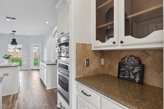 kitchen featuring appliances with stainless steel finishes, dark stone counters, decorative light fixtures, white cabinets, and dark hardwood / wood-style floors