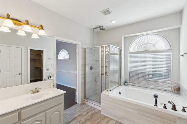 bathroom featuring plus walk in shower, vanity, hardwood / wood-style flooring, and a wealth of natural light