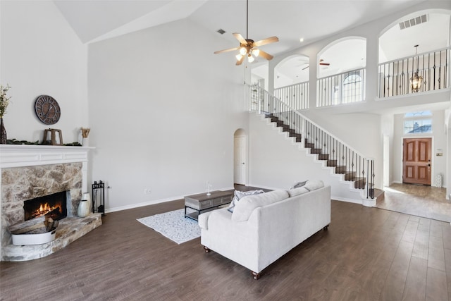 living room featuring a fireplace, dark hardwood / wood-style floors, high vaulted ceiling, and ceiling fan