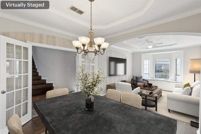 dining space with ceiling fan with notable chandelier, dark hardwood / wood-style floors, a raised ceiling, and ornamental molding