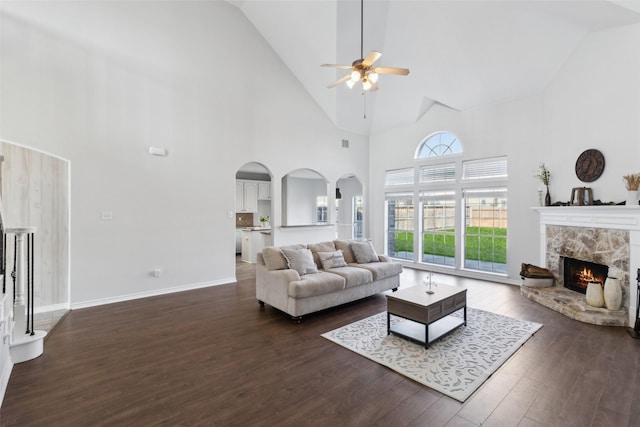 living room with a fireplace, dark hardwood / wood-style flooring, high vaulted ceiling, and ceiling fan