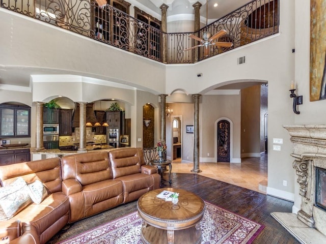 living room with decorative columns, ornamental molding, a premium fireplace, tile patterned flooring, and a high ceiling