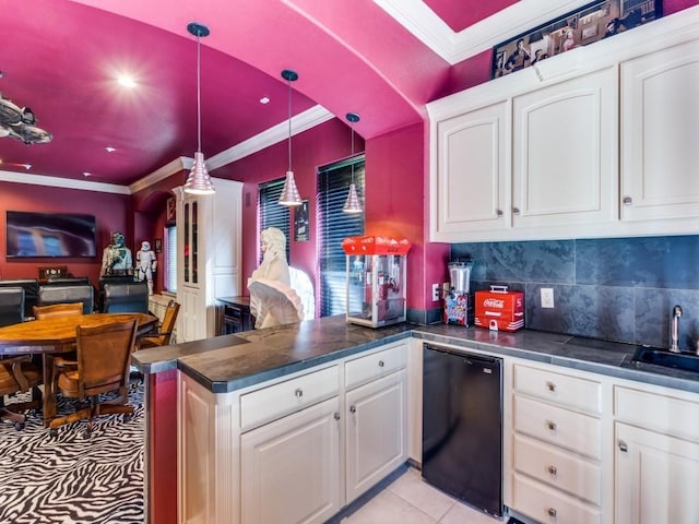 kitchen featuring kitchen peninsula, black fridge, pendant lighting, light tile patterned floors, and white cabinets