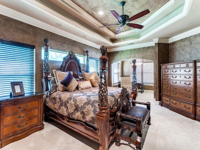 bedroom featuring a tray ceiling, ceiling fan, crown molding, and light colored carpet