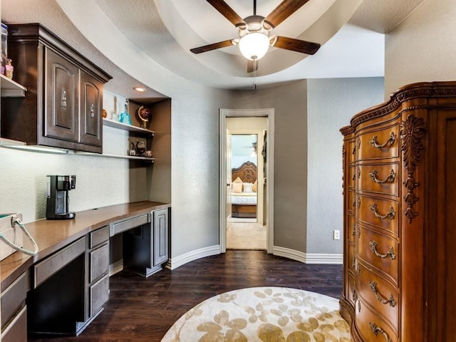 kitchen featuring ceiling fan, dark wood-type flooring, built in desk, and dark brown cabinets