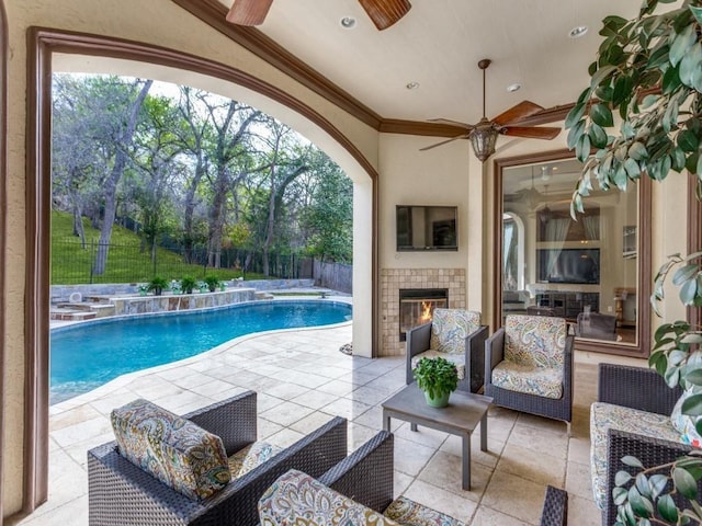 view of pool with a tile fireplace, ceiling fan, and a patio