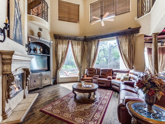 living room featuring ceiling fan, a towering ceiling, a healthy amount of sunlight, and hardwood / wood-style flooring