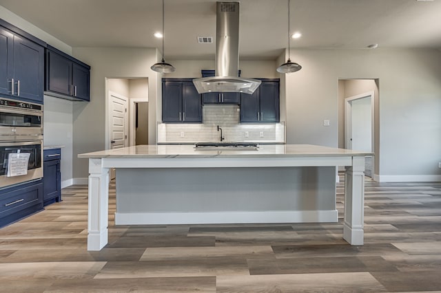 kitchen featuring island range hood, hardwood / wood-style floors, hanging light fixtures, and blue cabinets