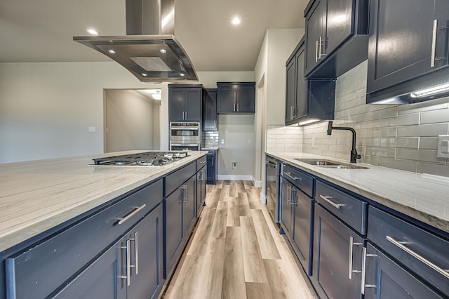 kitchen featuring sink, island exhaust hood, light wood-type flooring, decorative backsplash, and appliances with stainless steel finishes